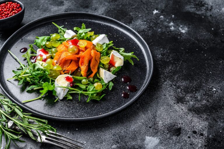 Autumn salad with baked pumpkin and brie cheese. Healthy vegan food concept. Black background